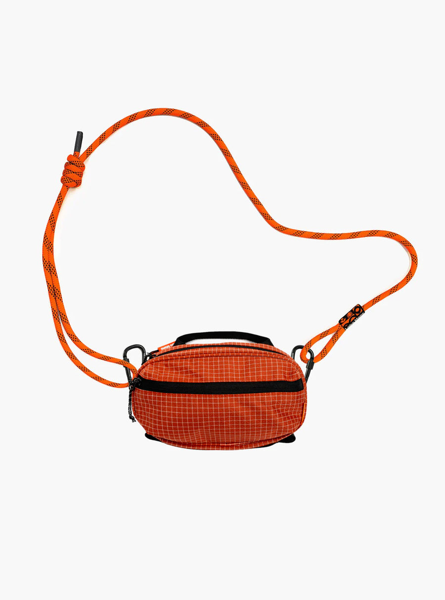 Sling Bag - Medium in Chili with an orange rope strap.