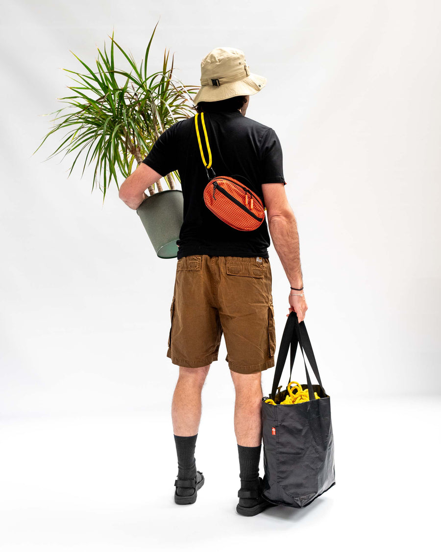Sling Bag - Medium in Chili, worn on the back.