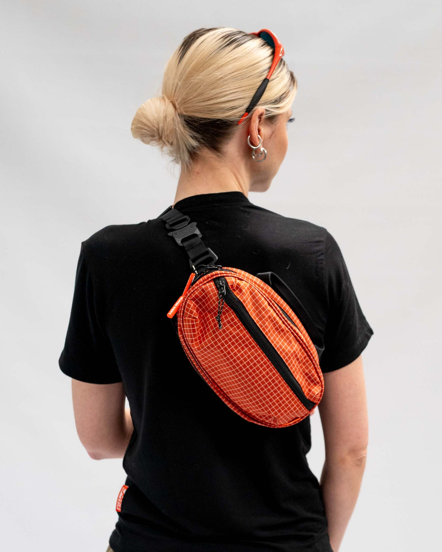 Sling Bag - Medium in Chili, worn on the back with a black rope strap.