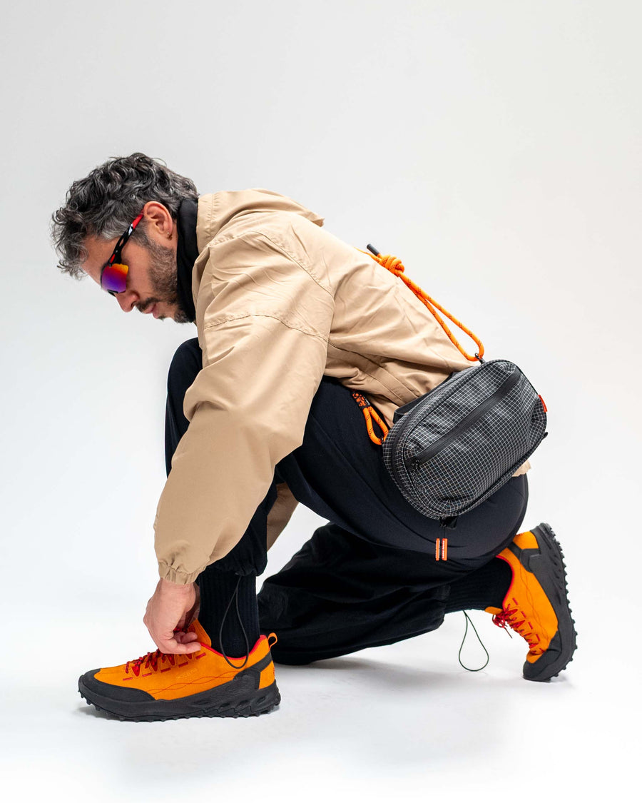 Sling Bag - Large in Black with an orange rope strap, worn across the back.