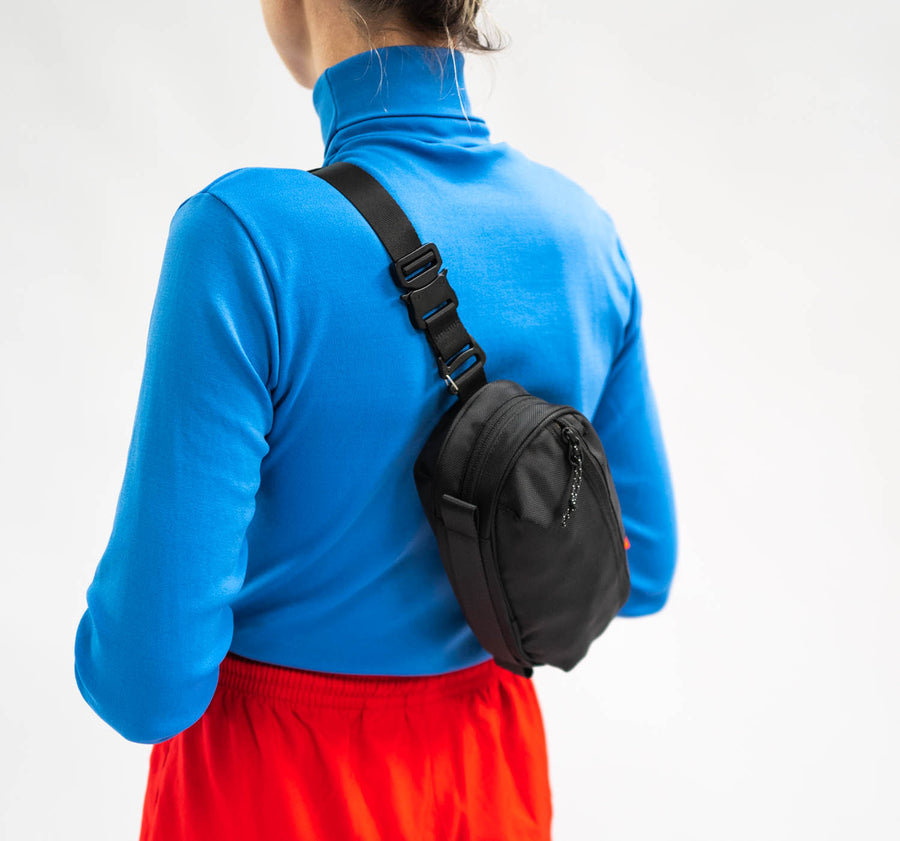 A black sling bag worn on a flat strap