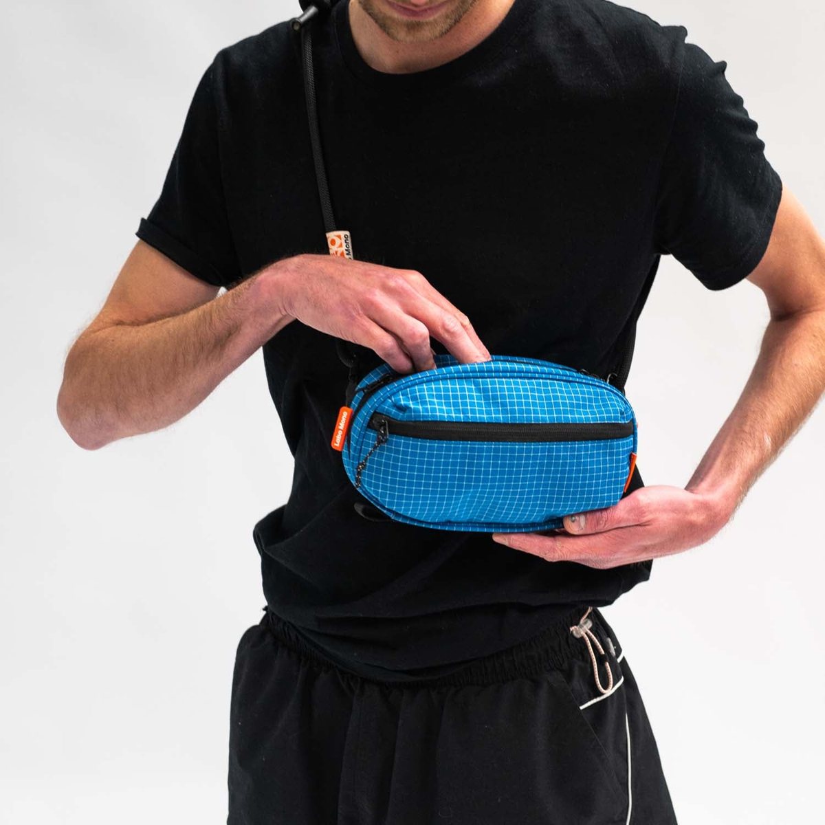 A blue sling bag worn across the body, a hand reaching into it